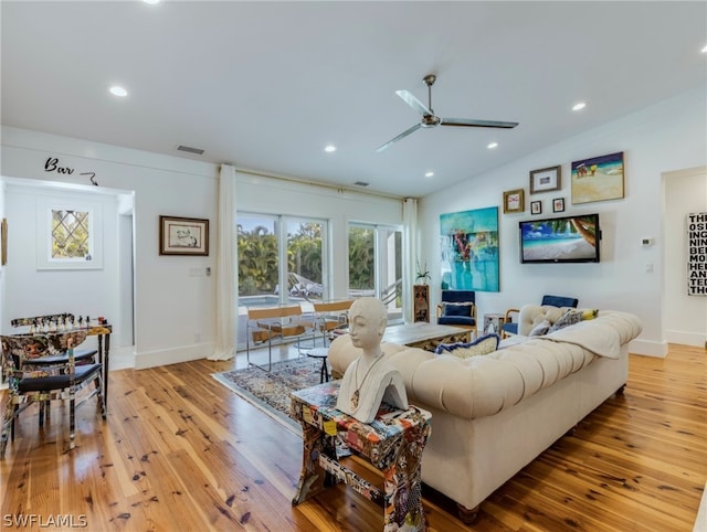 living room featuring ceiling fan, vaulted ceiling, and light hardwood / wood-style flooring