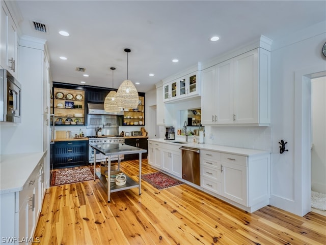 kitchen featuring decorative light fixtures, appliances with stainless steel finishes, white cabinetry, and light hardwood / wood-style floors