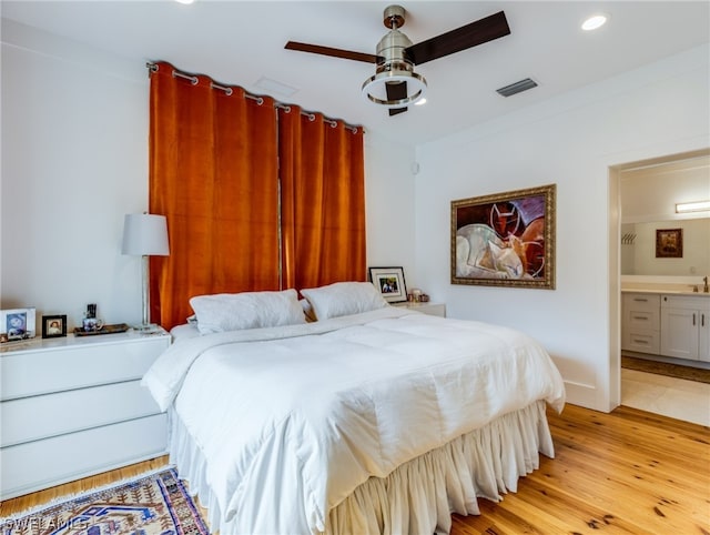 bedroom featuring connected bathroom, light hardwood / wood-style floors, and ceiling fan