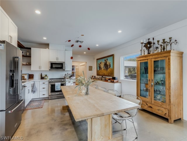 kitchen with a kitchen island, stainless steel appliances, white cabinetry, and a breakfast bar