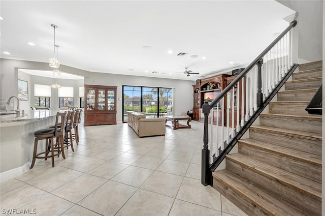 staircase featuring ceiling fan with notable chandelier, sink, and light tile floors