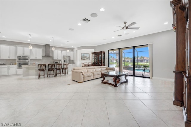 living room with light tile floors, ornamental molding, and ceiling fan