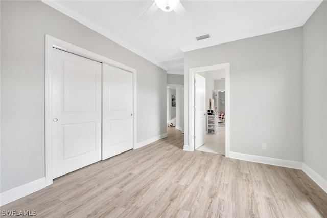 unfurnished bedroom with crown molding, light hardwood / wood-style floors, a closet, and ceiling fan