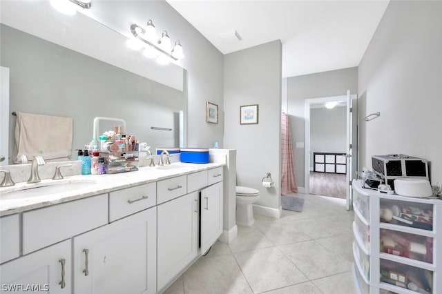 bathroom featuring toilet, double vanity, and tile floors