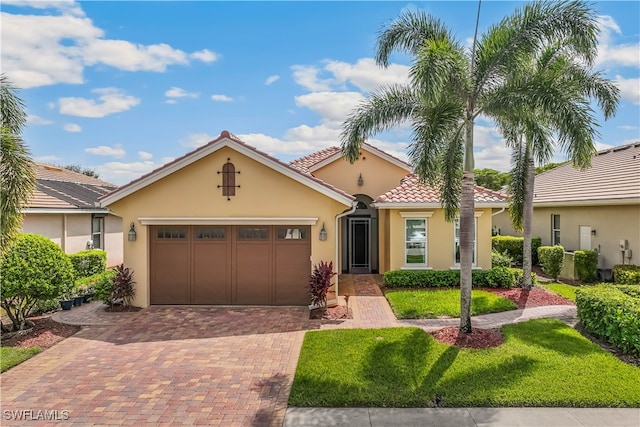 mediterranean / spanish home featuring a garage and a front yard