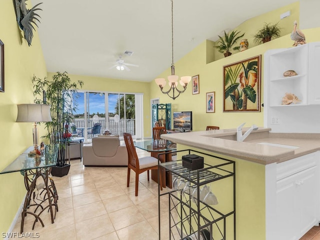 kitchen featuring light tile floors, white cabinetry, ceiling fan with notable chandelier, and pendant lighting