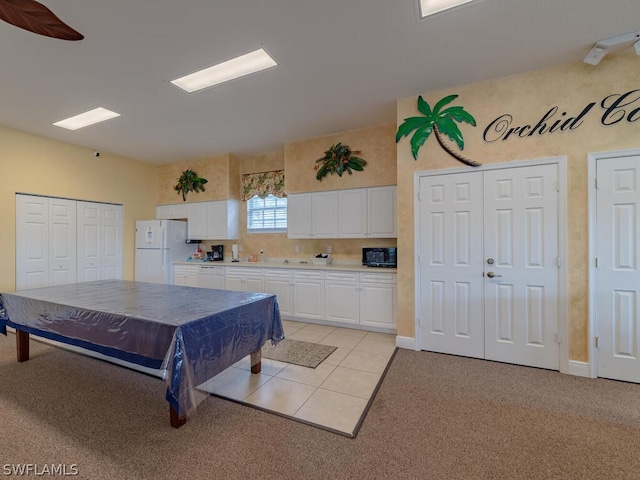 interior space with ceiling fan, white refrigerator, white cabinets, light carpet, and tasteful backsplash