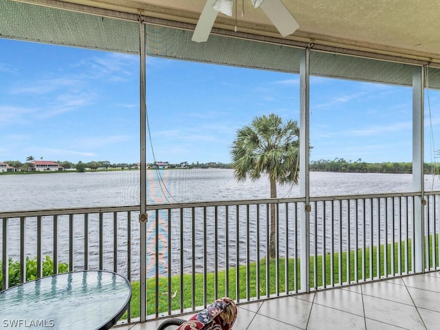 unfurnished sunroom featuring ceiling fan and a water view