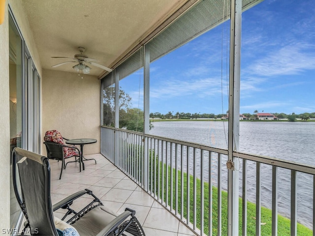 sunroom featuring ceiling fan and a water view