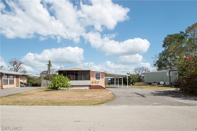 manufactured / mobile home featuring a front lawn, a carport, and a sunroom