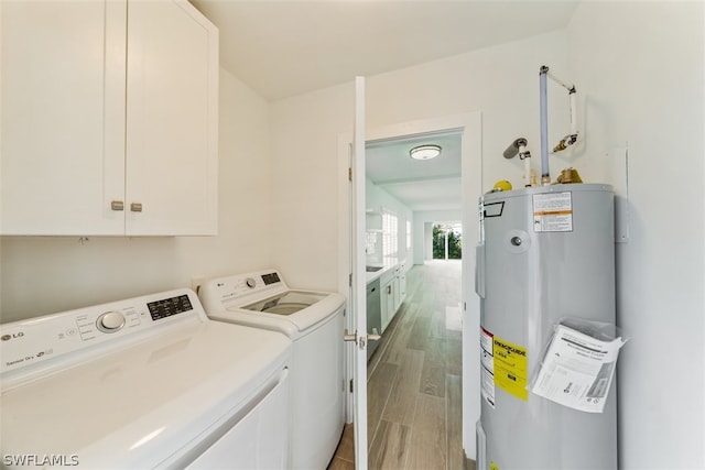 washroom featuring washer and clothes dryer, light hardwood / wood-style floors, cabinets, and electric water heater