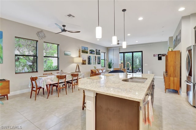 kitchen with recessed lighting, a sink, visible vents, an island with sink, and stainless steel fridge