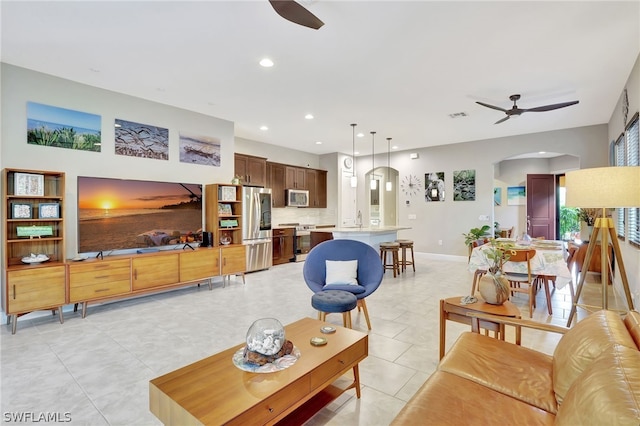 living area featuring light tile patterned floors, baseboards, arched walkways, a ceiling fan, and recessed lighting