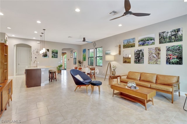 living room with arched walkways, a ceiling fan, and recessed lighting