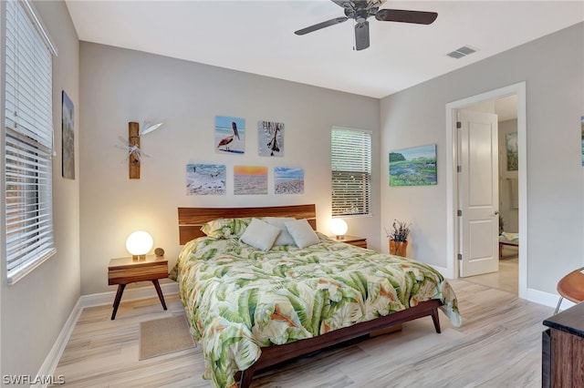 bedroom featuring visible vents, ceiling fan, light wood-style flooring, and baseboards