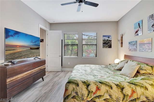 bedroom with baseboards, a ceiling fan, and light wood-style floors