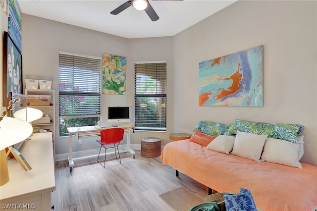 living area with a ceiling fan, baseboards, and wood finished floors