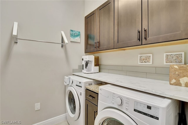 laundry area featuring washing machine and dryer, cabinet space, and baseboards