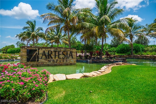 community sign featuring a yard and a small pond