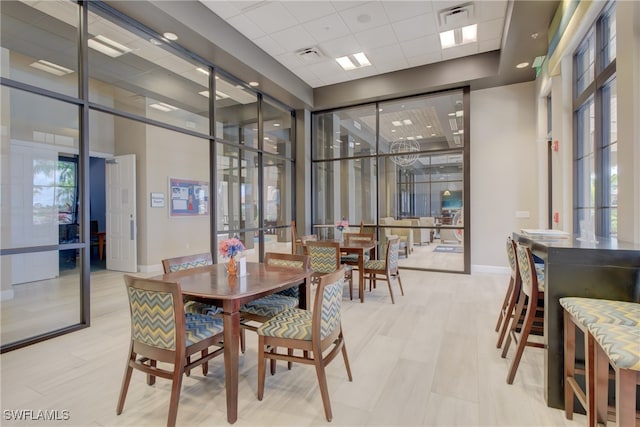 dining space with a paneled ceiling, baseboards, visible vents, and a high ceiling