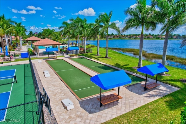 view of property's community featuring a lawn, a water view, and fence