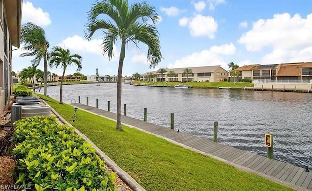 view of dock with a lawn and a water view