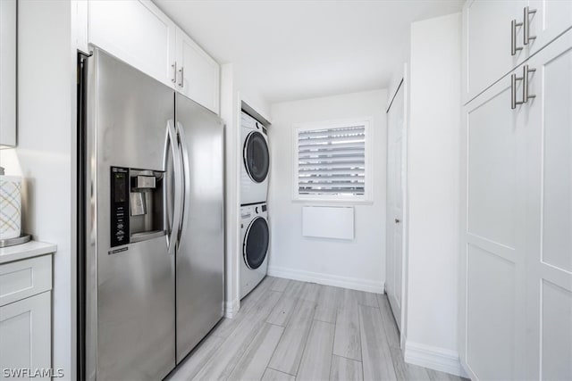 clothes washing area featuring stacked washer / drying machine and light hardwood / wood-style flooring