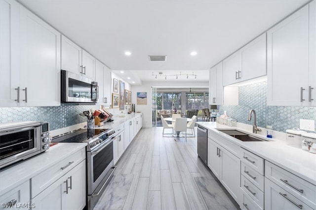 kitchen featuring white cabinets, decorative backsplash, sink, and appliances with stainless steel finishes