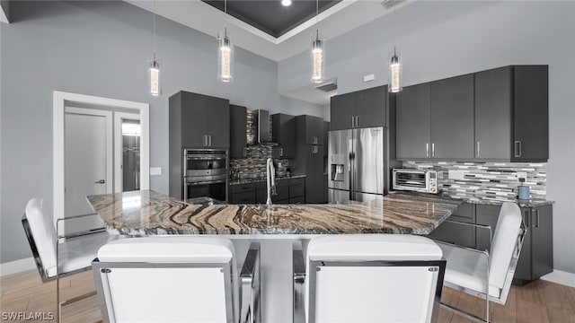 kitchen featuring hanging light fixtures, a kitchen breakfast bar, a high ceiling, and appliances with stainless steel finishes