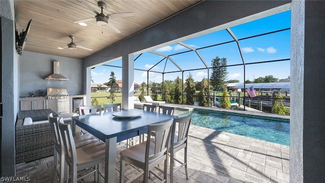 exterior space featuring an outdoor kitchen, ceiling fan, a patio, and a lanai