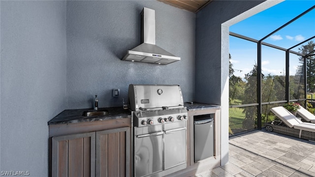 kitchen with dark stone countertops, fridge, sink, and wall chimney range hood