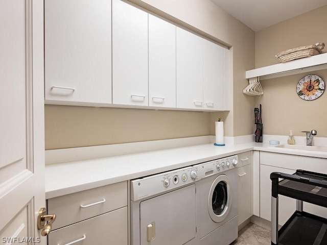 laundry room with cabinets, washing machine and dryer, and sink