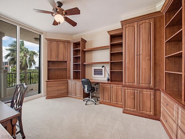 home office featuring ornamental molding, light colored carpet, ceiling fan, built in desk, and a wall of windows