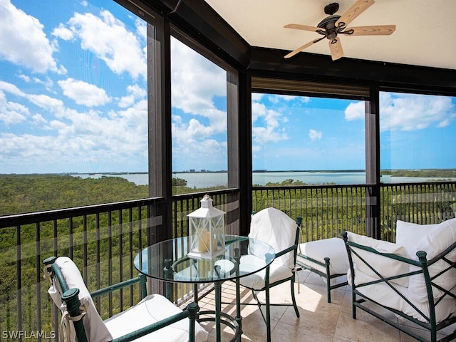 sunroom / solarium with ceiling fan and a water view