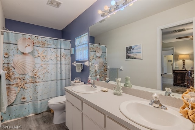 bathroom with hardwood / wood-style flooring, double sink vanity, and toilet