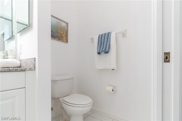 bathroom with toilet, vanity with extensive cabinet space, and tile flooring