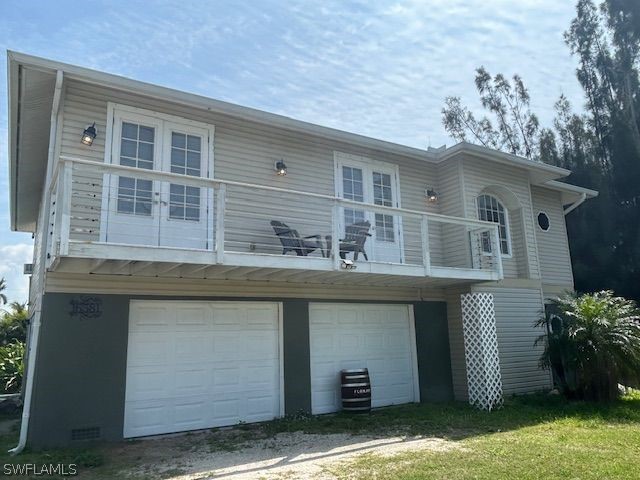 rear view of property with a garage and a balcony