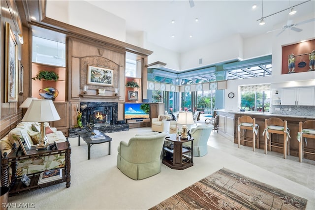 tiled living room featuring ceiling fan, a towering ceiling, and a fireplace