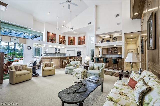 carpeted living room with ceiling fan and high vaulted ceiling