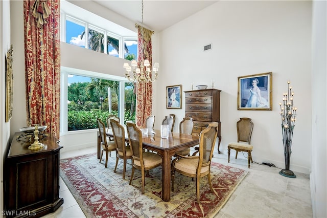 dining space featuring a notable chandelier, light tile patterned flooring, and a high ceiling