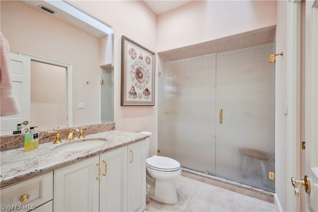 bathroom featuring tile patterned floors, vanity, a shower with shower door, and toilet