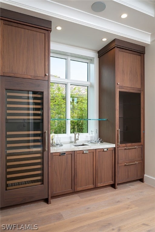 bar featuring beverage cooler, light wood-type flooring, a sink, and recessed lighting