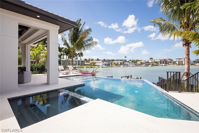 view of swimming pool featuring a water view, a patio area, and a pool with connected hot tub