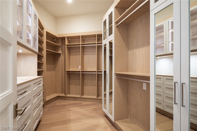 walk in closet with light wood-style floors