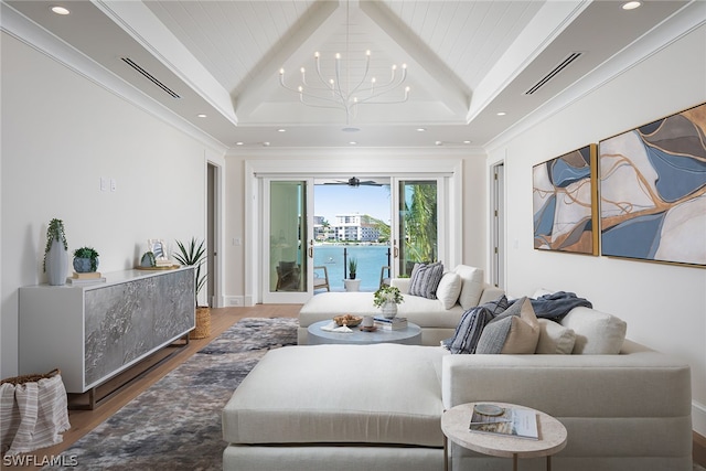 living area with visible vents, lofted ceiling, ornamental molding, wood finished floors, and an inviting chandelier