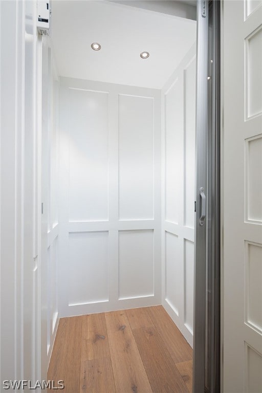 hallway featuring light wood-style floors, recessed lighting, and a decorative wall