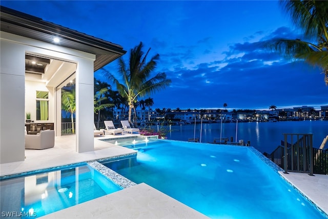 view of swimming pool featuring a patio area, a water view, and a pool with connected hot tub