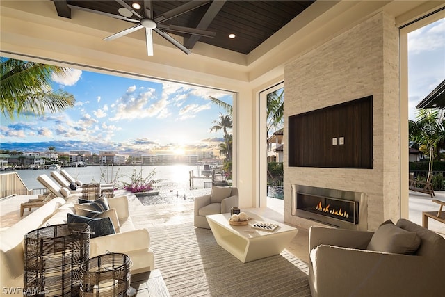 view of patio / terrace featuring ceiling fan, an outdoor living space with a fireplace, and a water view