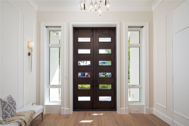 entrance foyer featuring a chandelier, french doors, wood finished floors, and ornamental molding