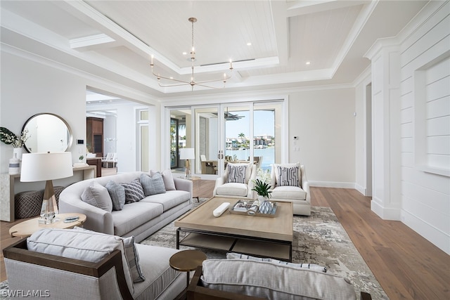 living room featuring a notable chandelier, baseboards, wood finished floors, and crown molding